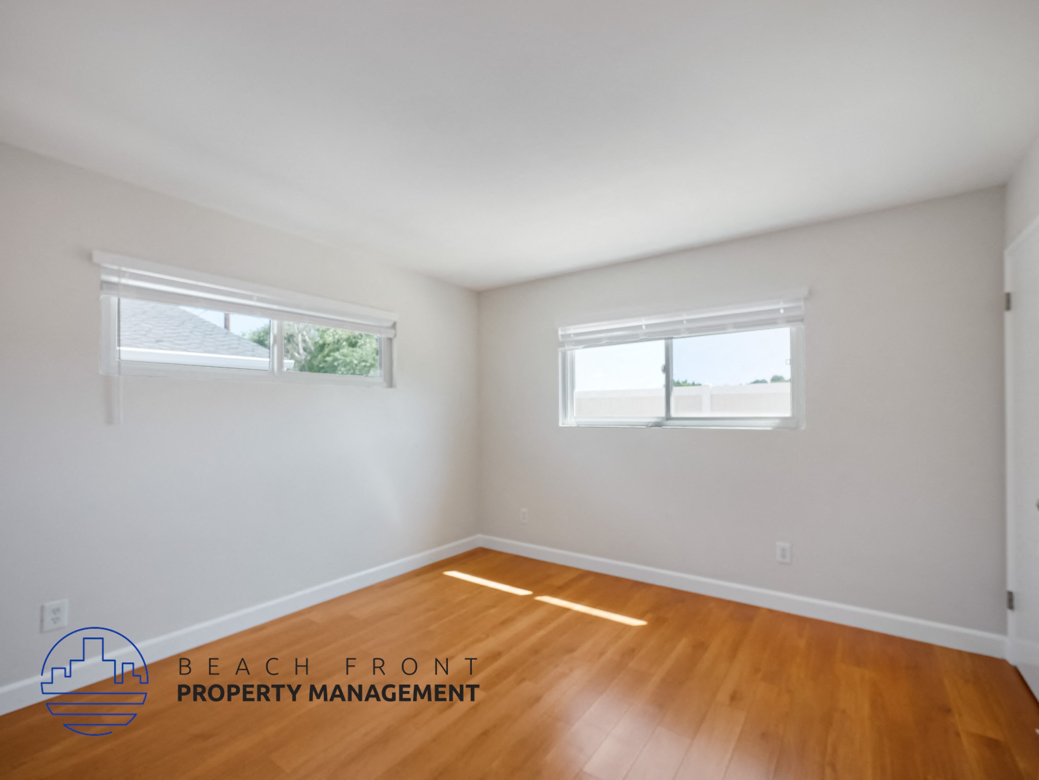 A room with wooden floors and two windows, one of which is open.